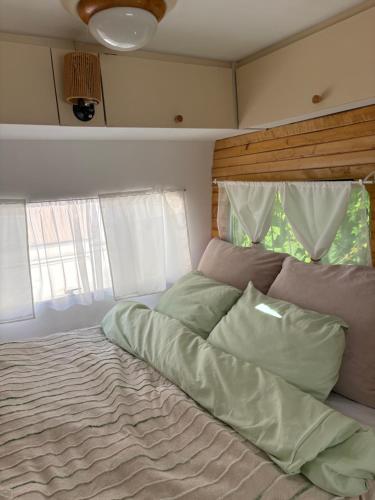 a large bed in a bedroom with two windows at Przyczepa Kempingowa Beige in Jastarnia