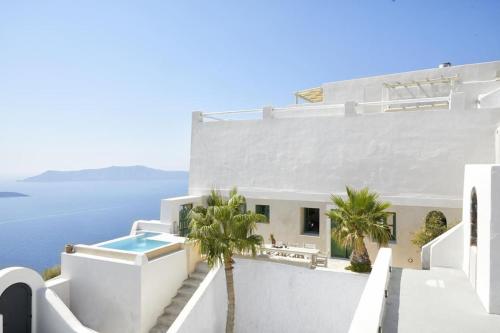 a white house with a swimming pool and palm trees at Villa Murat in Fira