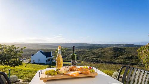 a table with a plate of food and a bottle of wine at Plettenvale Wines in Plettenberg Bay