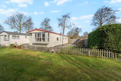 a house with a wooden fence in a yard at Chalet Huffels P12 - Camping De Nollen Callantsoog in Callantsoog