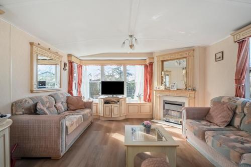 a living room with two couches and a tv at Chalet Huffels P12 - Camping De Nollen Callantsoog in Callantsoog