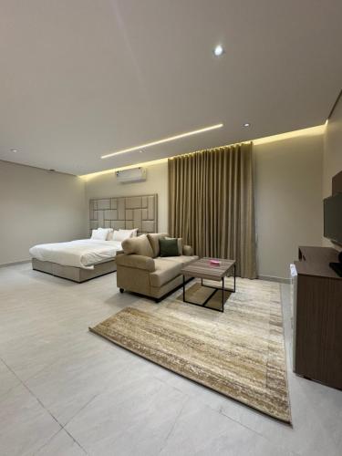 a bedroom with a bed and a couch and a tv at شقق طلال الفندقية- Talal hotel apartments in Al-ʿUla