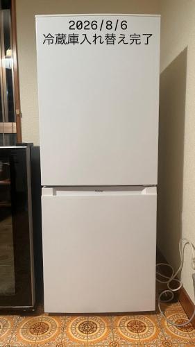 a white refrigerator with a sign on top of it at 天然温泉付 一棟貸し最大12名 近隣施設事前予約で バーベキュー 花火 和羽灯屋 ナウヒヤ in Fuefuki