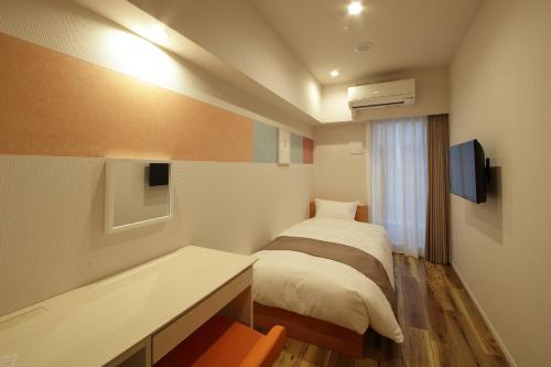 大阪市にあるSARASA HOTEL心斎橋のベッド、机、テレビのある寝室