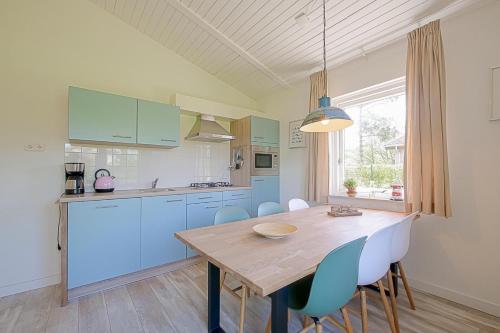a kitchen with a wooden table and blue cabinets at Vakantiehuis Duynloper - Julianadorp aan Zee in Julianadorp
