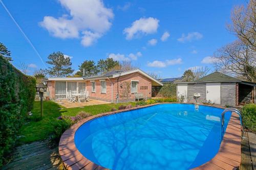 a swimming pool in front of a house at Vakantiehuis Springtij met privé zwembad - Julianadorp aan Zee in Julianadorp