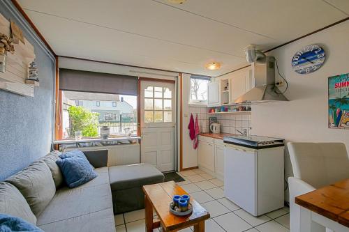 a living room with a couch and a kitchen at Tiny House Petite - Callantsoog aan Zee in Callantsoog