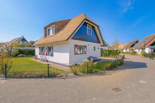 a white and blue house with a fence at Villa Schaut - Villapark De Buitenplaats Callantsoog aan Zee in Callantsoog