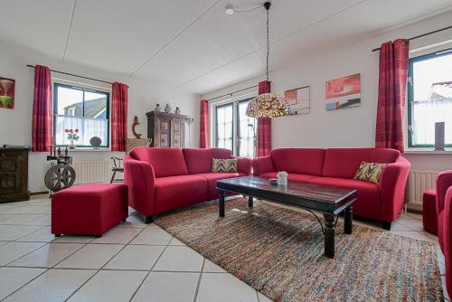 a living room with red couches and a coffee table at Villa Schaut - Villapark De Buitenplaats Callantsoog aan Zee in Callantsoog