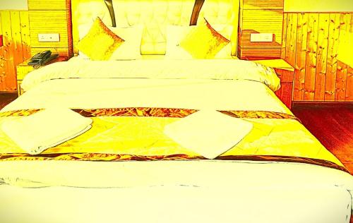 a bedroom with a large bed with yellow sheets at The Trisha Hotel in kolkata