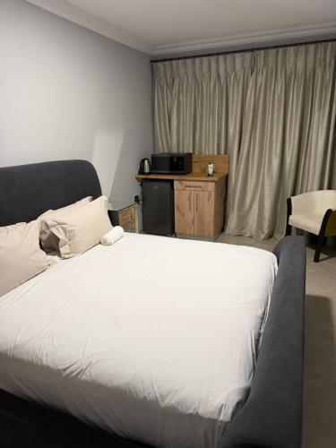 a bedroom with a large white bed and a window at Highveld Nook in Sasolburg