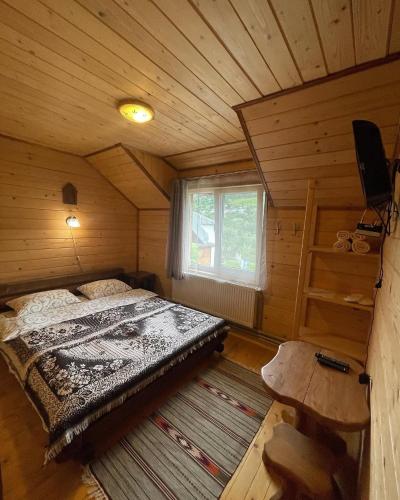 a bedroom with a bed in a wooden cabin at Chalet Rovenka in Verkhovyna