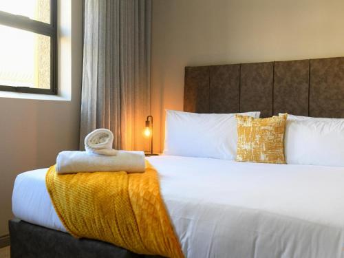 a hotel room with a bed with a towel on it at Next To Apartment Hotel in Pretoria