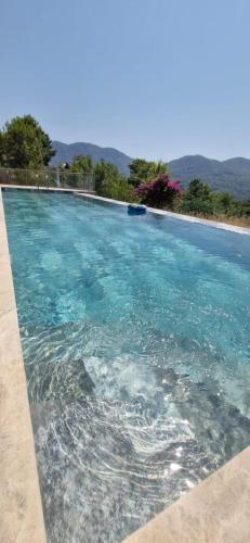 a swimming pool with blue water and mountains in the background at Iztuzu Sunset Villa in Gökbel