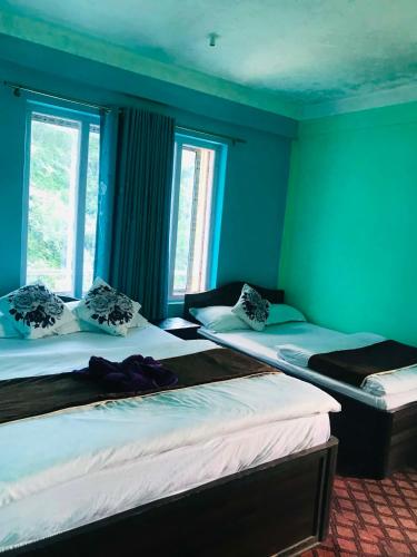 two beds in a room with blue walls and windows at Gauri Shanker Hotel and Lodge in Dharān Bāzār