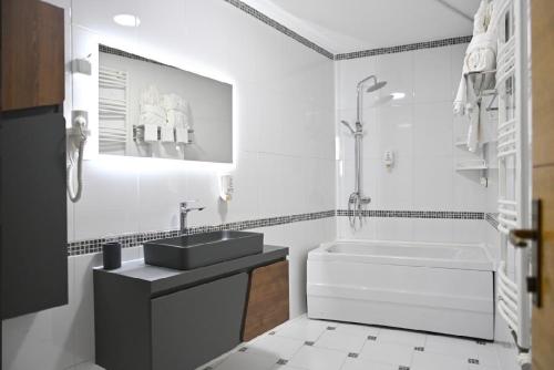 a white bathroom with a sink and a tub at Juna's Hotel in Prizren