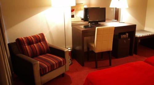 a room with a desk with a chair and a television at Hotel Dighton in Oliveira de Azemeis