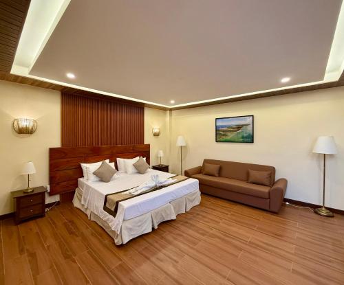 a large bedroom with a bed and a couch at Balai Amihan Bed & Breakfast in Talisay