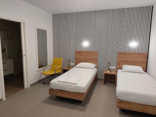 a room with two beds and a yellow chair at Hotel Amstar Simeria in Simeria