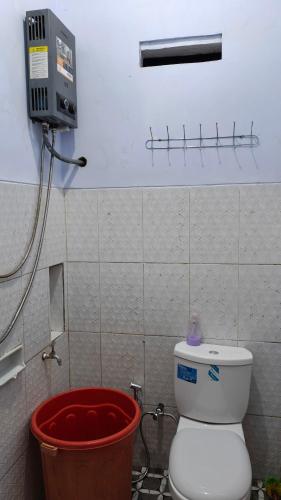a bathroom with a toilet and a red bucket at Bromo Jay House Homestay I in Sukapura
