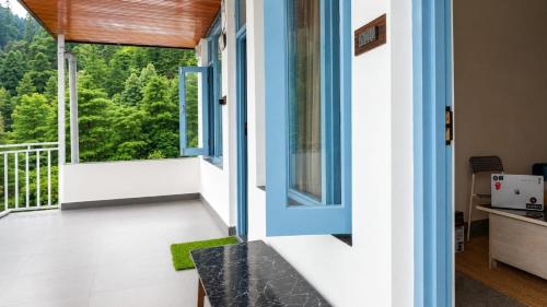 a room with a balcony with a view of trees at Le Refuge in McLeod Ganj