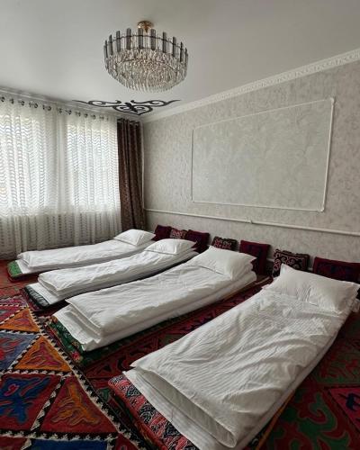 three beds in a room with a chandelier at datkaguesthouse in Kochkorka