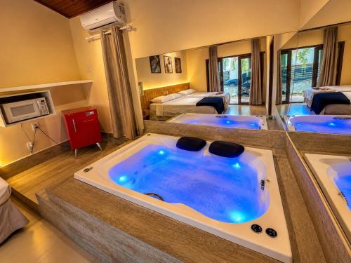 a room with a jacuzzi tub with four beds at Pousada Charmosa Lua Nova Pipa - Chales com Jacuzzi e Hidro in Pipa