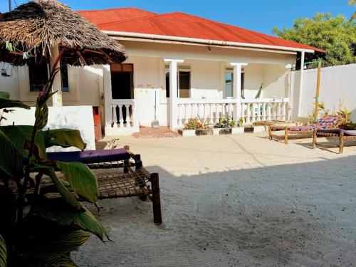 a house with a bench and a straw roof at Meama Paje Guesthouse in Paje
