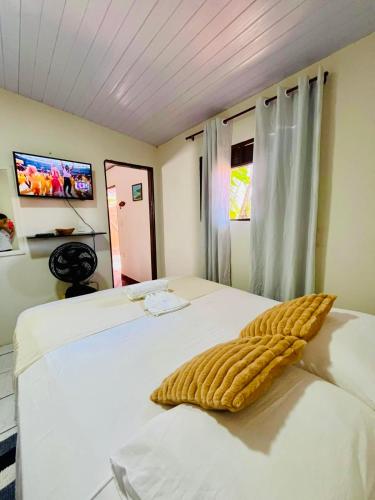 a bedroom with a bed with a yellow blanket on it at Chalé Rosani in Pipa