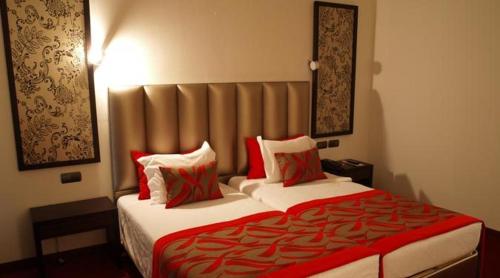 a bedroom with a large bed with red and white pillows at Hotel Dighton in Oliveira de Azemeis