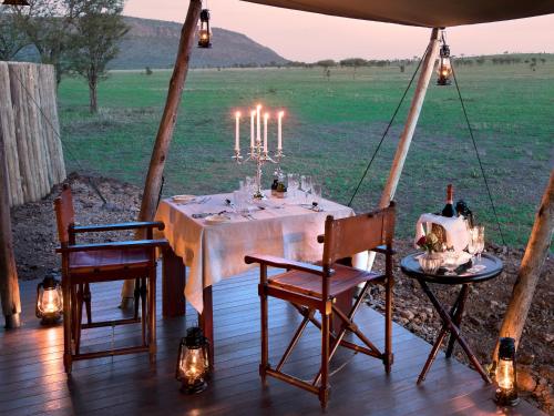 a dinner table in a gazebo with candles at One Nature Nyaruswiga Serengeti in Banagi