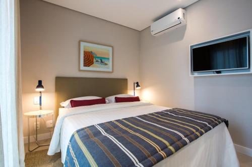 a bedroom with a bed and a flat screen tv at 2 quartos- Unique Ex-Estanconfor veja o mar do ap 1408 in Santos