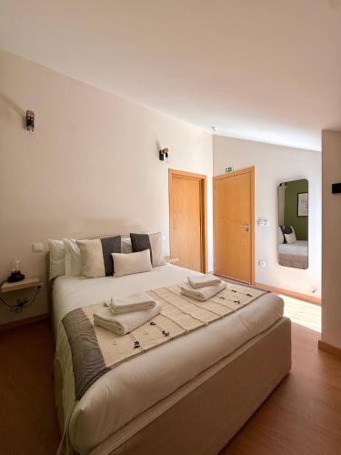 ein Schlafzimmer mit einem großen Bett und einem Spiegel in der Unterkunft Recanto do Cávado in Barcelinhos