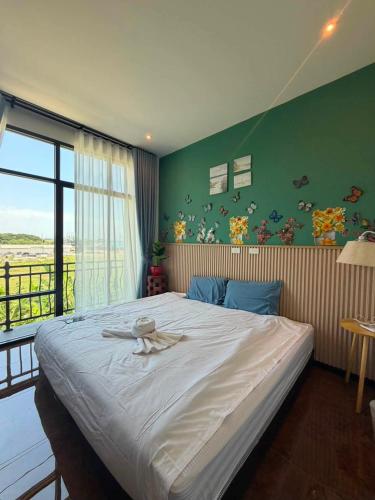 a bedroom with a large bed with a large window at ซันไบร์ท พลูวิลล่า 2 in Ban Huai Yai
