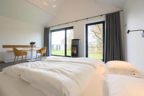 a white bedroom with a large bed and a table at Les Pieds au vert in Limbourg