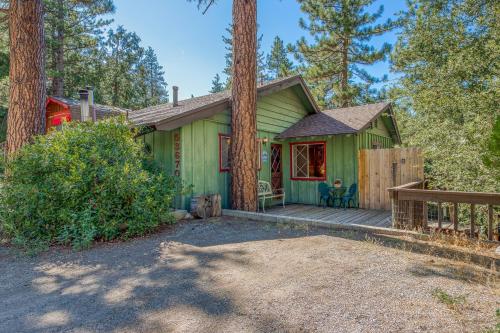 a green house with a wooden porch in the woods at Bear's Den in Idyllwild