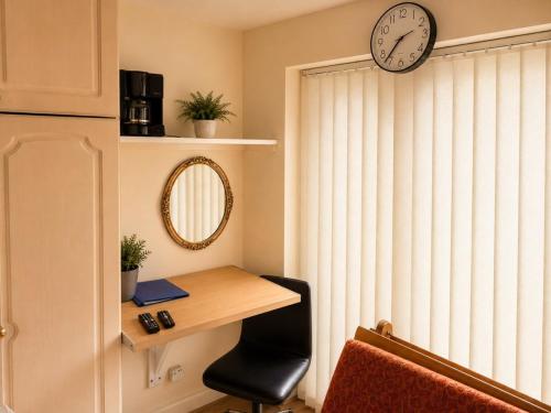 a room with a desk and a clock on the wall at Harman Suites 1 & 2 in Leeds