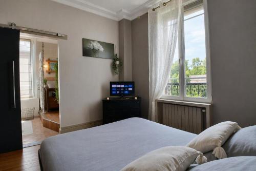 a bedroom with a bed and a window and a television at Gîte du Pré Nattier - Gisors centre in Gisors