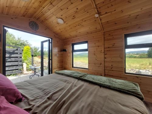 a large bed in a wooden room with windows at Knocknafallia in Cappoquin