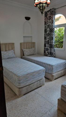two beds in a room with two windows at L'Echappée Belle in Sidi Boû el Fedâïl