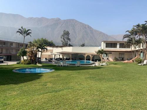 a resort with a pool and a building and mountains at El Angolo Chosica in Nicolas de Pierola