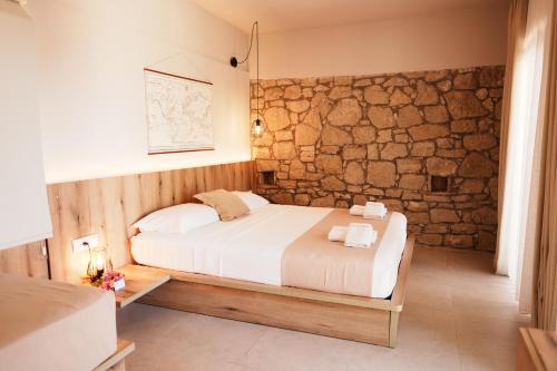 a bedroom with a bed and a stone wall at ARAMERAS Resort in Ksamil