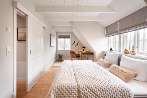 a bedroom with a large bed and a desk at Reethaus Nordgold in Oldsum