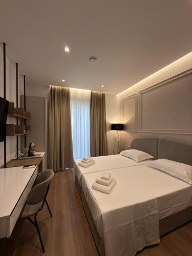 a bedroom with a large white bed and a desk at Eden Center Rooms in Durrës