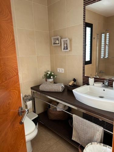 a bathroom with a sink and a toilet and a mirror at Tramuntana & Beach in Pollença