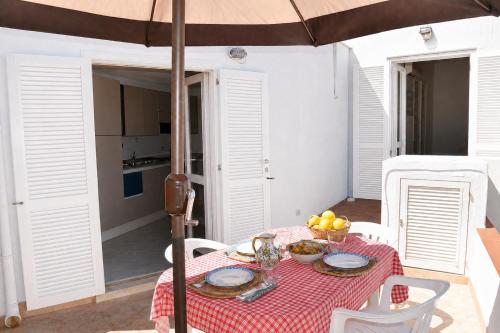 a table with a red and white table cloth and an umbrella at Maridea - Turritella in Ponza