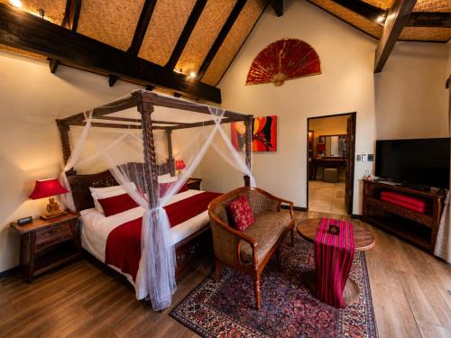 a bedroom with a canopy bed and a chair at The Zarafa in Hazyview