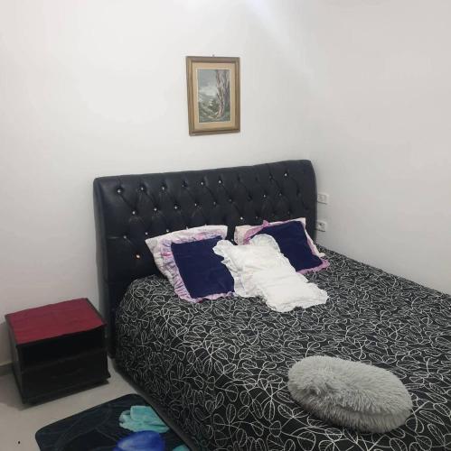 a bed with a black headboard and pillows on it at Immobilier Kimo in Tunis