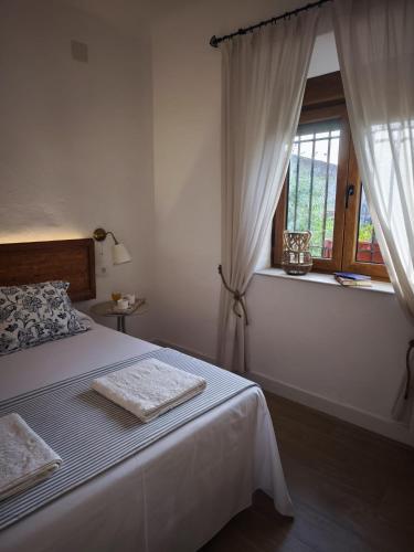 a white bedroom with a bed and a window at El Huerto de La Ermita in La Zubia