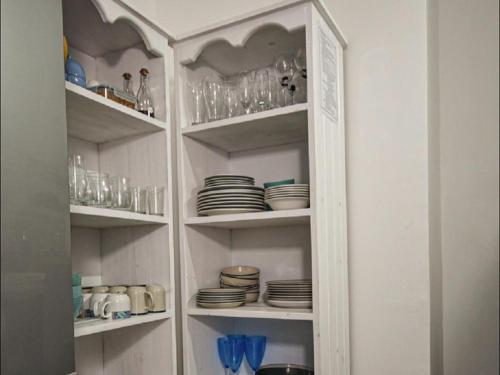 a white cabinet with plates and glasses on it at Lieflappie Seaview Stilbaai 400m to the beach in Stilbaai